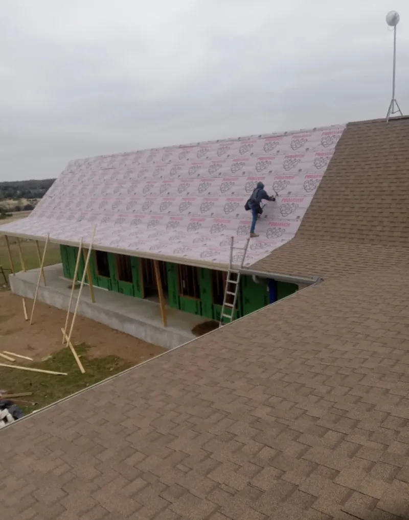 Worker preparing underlayment for a metal roof installation in Meadow Woods